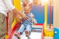 Happy young mother with her baby girl playing in colorful playground for kids. Mom with toddler having fun at summer park. Royalty Free Stock Photo