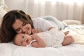 Happy young mother with her cute baby on bed at home Royalty Free Stock Photo