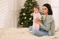 Happy young mother with her cute baby on bed at home, space for text. Winter holiday Royalty Free Stock Photo