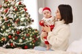 Happy young mother with her cute baby on bed, space for text. Winter holiday Royalty Free Stock Photo