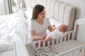 Happy young mother with her cute newborn baby near bedside crib at home Royalty Free Stock Photo