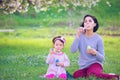 Happy young mother and her daughter blowing soap bubbles Royalty Free Stock Photo