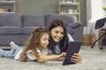 Happy young mother and her little daughter playing games on a digital tablet together Royalty Free Stock Photo