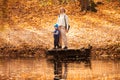 Happy young mother and her son spending time in the autumn park near the pond. Royalty Free Stock Photo