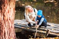 Happy young mother and her son spending time in the autumn park near the pond. Royalty Free Stock Photo