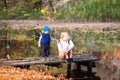 Happy young mother and her son spending time in the autumn park near the pond. Royalty Free Stock Photo