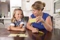 Happy young mother and her sweet and beautiful little daughter playing card game at home kitchen smiling and having fun together Royalty Free Stock Photo