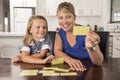 Happy young mother and her sweet and beautiful little daughter playing card game at home kitchen smiling and having fun together Royalty Free Stock Photo