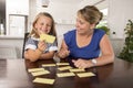 Happy young mother and her sweet and beautiful little daughter playing card game at home kitchen smiling and having fun together Royalty Free Stock Photo