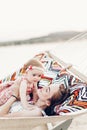 Happy young mother holding baby daughter in hands while relaxing in hammock with husband, hipster family concept, cute girl with Royalty Free Stock Photo