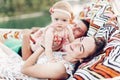 Happy young mother holding baby daughter in hands while relaxing in hammock with husband, hipster family concept, cute girl with Royalty Free Stock Photo