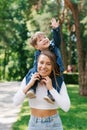 Happy young mother holds a cute baby in her arms, the family is having fun together on the street on a sunny summer day in the Royalty Free Stock Photo