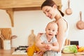 A happy young mother holds her little son in her arms, in the kitchen Royalty Free Stock Photo