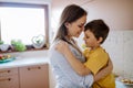 Happy young mother hugging her little son in kitchen at home. Royalty Free Stock Photo