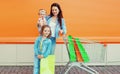 Happy mother and kids two little girls children with trolley cart and shopping bags in a city Royalty Free Stock Photo