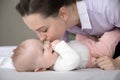Happy young mother kissing baby in bedroom. Royalty Free Stock Photo