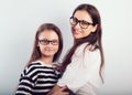 Happy young mother and lauging kid in fashion glasses hugging on empty copy space background. Family