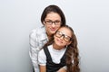 Happy young mother and lauging kid in fashion glasses hugging on empty copy space background. Family portrait