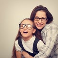 Happy young mother and lauging kid in fashion glasses hugging on