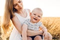 Happy young mother with little child playing in the ripening wheat field Royalty Free Stock Photo