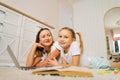 Happy young mother and little girl using laptop computer together lying on floor in children room with modern light Royalty Free Stock Photo