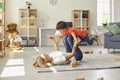 Happy young mother lying on carpet, holding her son on legs in raised hands and having fun at home Royalty Free Stock Photo