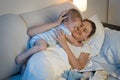 Happy young mother playing and embracing her baby boy in bed at Royalty Free Stock Photo