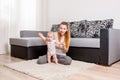 Happy young mother playing with her baby on the floor near the sofa Royalty Free Stock Photo