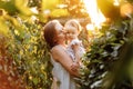Happy young mother playing and kissing her little baby daughter on sunshine warm spring or summer day. Beautiful sunset Royalty Free Stock Photo