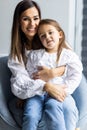 Happy young mother sit on chair hold in arms cute little daughter enjoy close tender family moment together