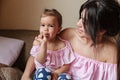 Happy young mother sitting on sofa with daughter eating candy Royalty Free Stock Photo