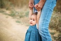 Happy young mother with a small daughter in hands, who is trying to make her first steps, outdoors background Royalty Free Stock Photo
