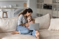 Happy young mother and small daughter watching funny cartoons.