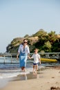 Happy young mother with son on a sunny day running by the sea. Rest on the beach. A happy family