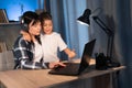 Happy young mother talking to son while working on laptop at home. boy looking for mom while typing on computer at night Royalty Free Stock Photo