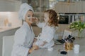 Happy young mother teacher her little daughter to do makeup. Culry small girl applies beauty patches under eyes to mom use beauty Royalty Free Stock Photo