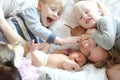 Happy Young Mother and Three Children Snuggling on Bed Royalty Free Stock Photo