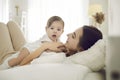 Happy young mother together with her sweet adorable baby cuddling on bed at home Royalty Free Stock Photo