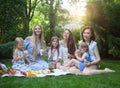 Happy young mothers and daughters having picnic in summer park