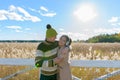 Happy young multi ethnic couple embracing each other against scenic view of autumn bulrush field