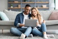 Happy Young Multicultural Couple Relaxing With Laptop On Floor At Home Royalty Free Stock Photo
