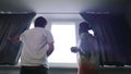 Happy young multiracial couple standing near window and opening curtains. Slow motion