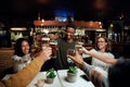 Happy young multiracial group of friends in casual clothing toasting with drinks at table Royalty Free Stock Photo