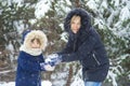 Happy young mum and her little daughter in winter hats in snow forest at snowflakes background. outdoors winter leisure and Royalty Free Stock Photo