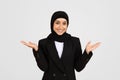 Happy young muslim businesswoman in suit and hijab raising hands up with open palms, rejoicing and smiling Royalty Free Stock Photo