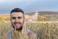 Happy young natural man relaxing on wheat summer field and smiling. Harvest concept Royalty Free Stock Photo