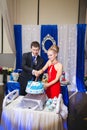 Happy young newlywed couple cutting wedding cake at banquet Royalty Free Stock Photo
