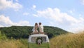 Happy young newlyweds bride and groom on the top of rerto wedding bus in the sunny summer field. Tender moment of love