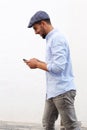 Happy young North African man walking and looking at cellphone against white background Royalty Free Stock Photo