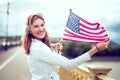 Young patriot woman with smiling and stretching USA flag